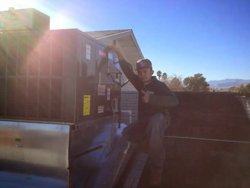 HVAC technician performing Air Duct Repair on a rooftop unit in Madras